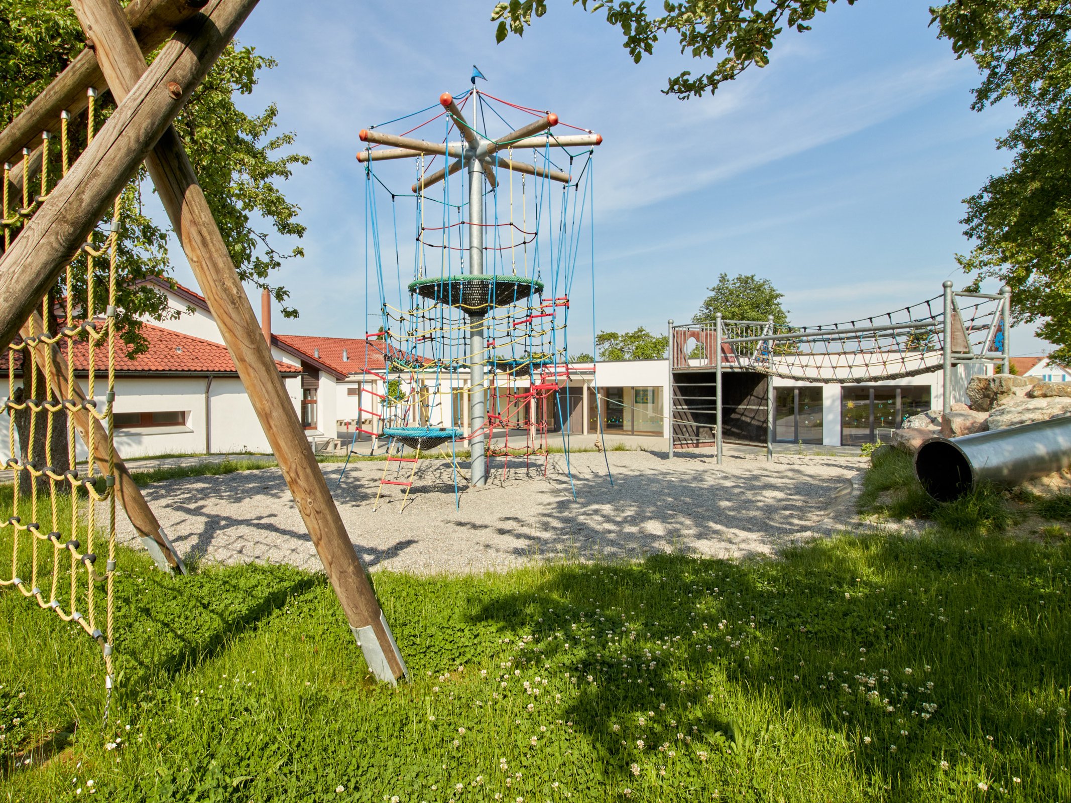 Spielbereich der Rosenbach Grundschule mit verschiedenen Klettergerüsten bei Sonnenschein.