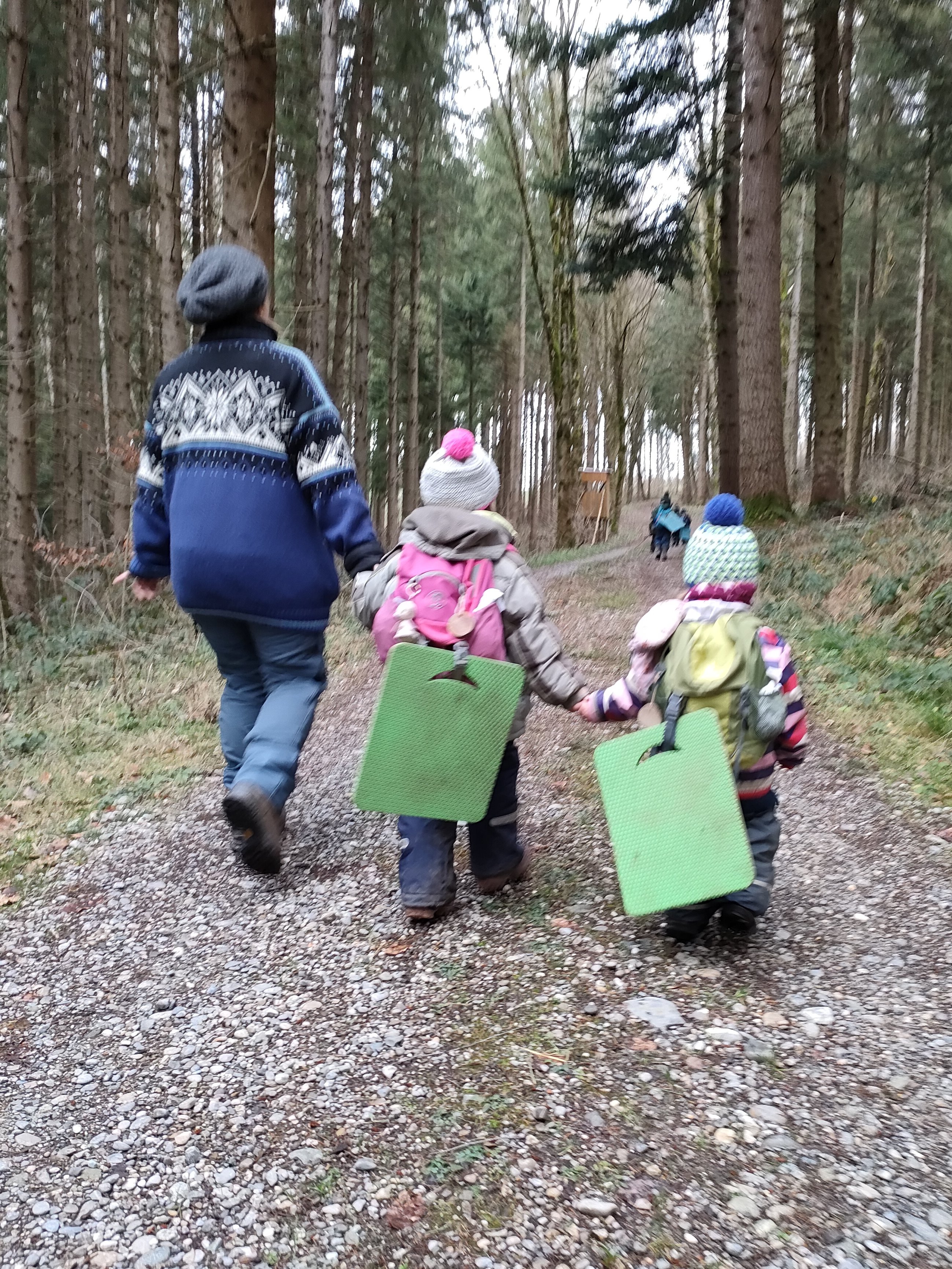 Kinder auf laufen gemeinsam mit Erzieherin auf einem Waldweg